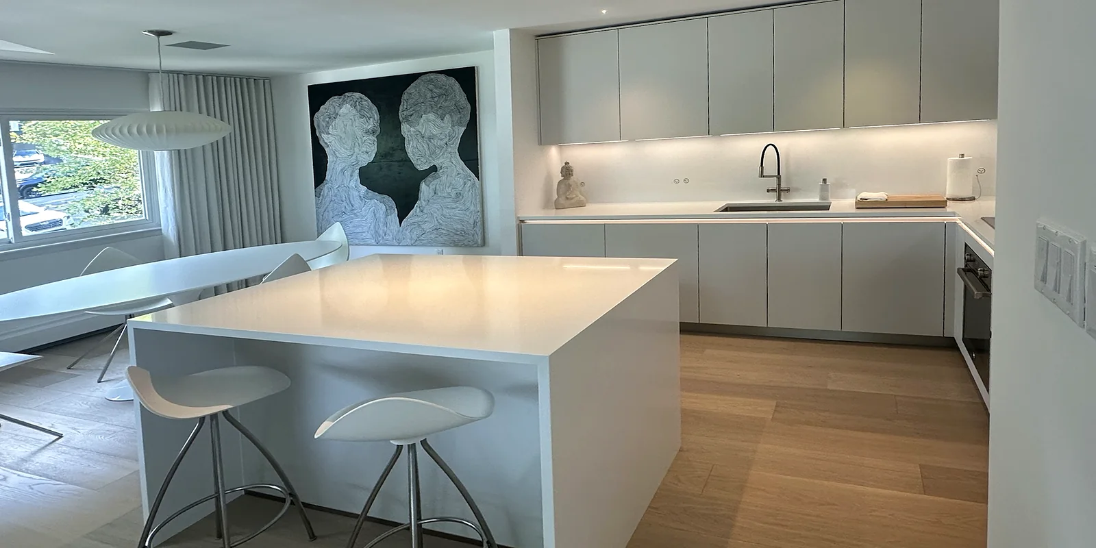 Spotless finished kitchen and dining area with a white waterfall island and bar stools