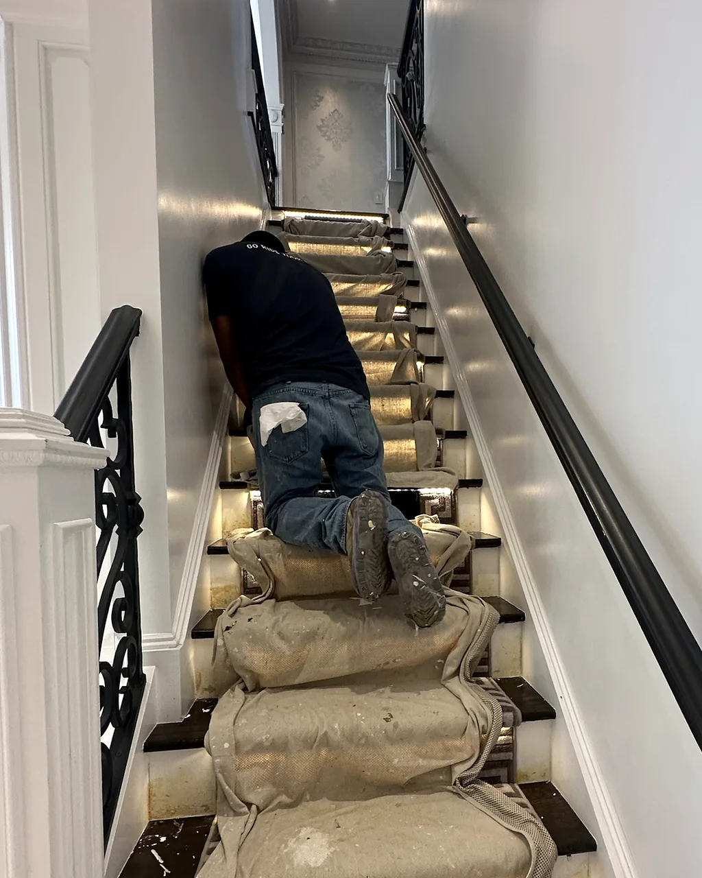 Painter at work in a stair hall with drop cloths covering every tread and the railings left clean